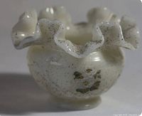 Front view of white ruffled glass vase with speckled surface and floral design.