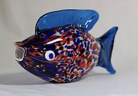 Side view of fish figurine showing multicolor speckled body with blue dorsal fin and visible details of eyes and mouth.