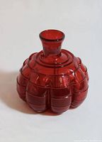 Front view of the red art glass decorative piece with rounded, textured segmented body and narrow neck.