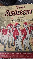 Close-up photo of the colorful illustrated cover of 'Franz Schubert and his Merry Friends' book.