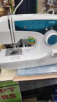 Side view of the Brother XL 2600 sewing machine showing the stitch selection panel with multiple stitch options and rotary dial.