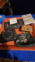 Overview of lot including three black leather wallets, a wood and painted glass trinket box, glass candy figurine, and bracelet