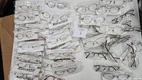 Multiple pairs of new Rimonzzi glasses frames packed in plastic, assorted kids and adult sizes, mostly metal frames.
