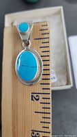Close-up front view of the larger pendant with turquoise set in sterling silver, showing measurement scale for size reference.