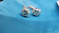 Pair of rope knot design sterling silver cufflinks on a blue fabric background