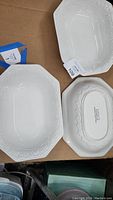 Top view of three rectangular white ceramic serving bowls showing embossed detail and their size.