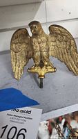 Front view of the heavy brass eagle flag ornament showing detailed feather and head shaping with mounting hardware below.