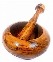 Side angled photo showing olive wood mortar with pestle resting inside bowl, highlighting wood grain and polished surface.