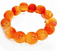 Close-up photo of polished round carnelian beads on stretch bracelet showing shiny, smooth surface and natural color variations.