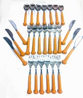 Full set of 25 flatware pieces including forks, spoons, and knives with orange handles laid out on white surface.