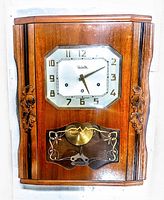 Front view of complete clock showing wood case, dial and glass door