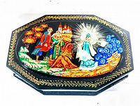 Top view showing the box lid with detailed hand painted Russian folk art scene and gold ornamental border on black lacquer base.