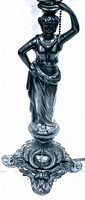 Close-up of the female figure on the base of the lamp, showing detailed draped clothing, head tilted back, and arm raised with pull chain.