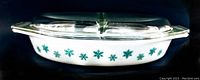 Side view of opaque white divided Pyrex casserole dish with teal snowflake pattern and clear lid on top
