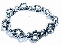 Silver chain bracelet with twisted and smooth circular links laid flat showing clasp and overall shape.