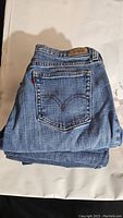 Folded blue denim Levi's women's jeans with back pocket featuring distinctive arcuate stitching and leather brand patch on waistband.