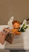 Front and slightly angled view of the small angel figurine showing facial details, mistletoe, and tag.