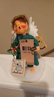 Close-up image of the Annalee Naughty Angel doll showing face and attached tags, displaying the detail and new condition with tags.