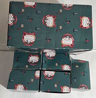 Five boxes wrapped in green holiday-themed paper with Blue Sky Clayworks label visible on some boxes.