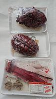 Photo showing packaged bloody heart, brain, and severed arm on foam trays