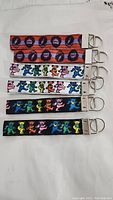 Six Grateful Dead lanyards laid flat side by side showing designs of dancing bears and lightning bolt skulls