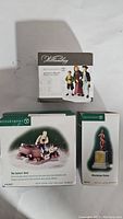Three Department 56 New England Village Series boxed figurines: Going to Church, The Sailors' Knot, Minuteman Statue.