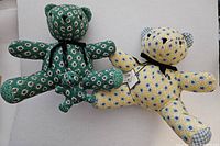 Pair of Vera Bradley bear dolls, one in green pattern and the other in yellow pattern, laid side by side.