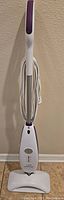 Full view of upright white and purple Sienna Luna steam mop with cord wrapped around handle.
