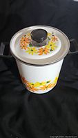 Front view of the vintage Ekco Country Garden porcelain pot with lid and floral pattern in orange and yellow flowers.