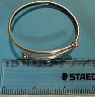 Sterling silver bangle bracelet laid flat next to a ruler showing approximately 6.5 cm diameter.