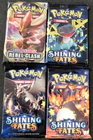 Front view showing all four sealed Pokémon card booster packs from Sword & Shield Rebel Clash and Shining Fates series, each with distinct Pokémon artwork.