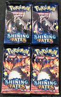 Front view of four Pokémon Shining Fates booster packs, two featuring Charizard and two with dark dragon Pokémon.