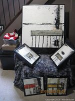 Full view of 5 paintings arranged on dark textured cloth, highlighting different sizes and abstract chair/table imagery