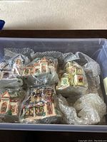 Photo of multiple ceramic Christmas village houses wrapped in bubble wrap inside container.