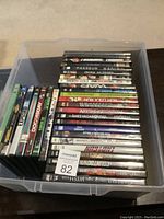 Photo showing multiple DVDs stacked in a clear plastic container with visible titles and spines.
