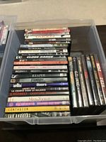 Container with 31 DVDs showing visible titles including Taken, Crash, Prison Break, Close Range, Insomnia, Standoff, The Doors, Contagion, San Andreas