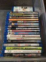 Photo showing stacked Blu-ray and DVD cases with movie titles visible in container.