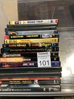 Stack of DVD cases inside transparent container, titles visible on spines