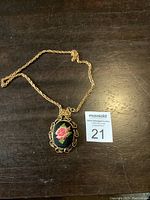 Full view of gold finish necklace with oval floral needlepoint pendant