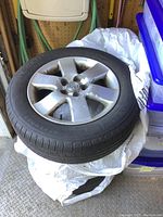 Stack of tires on rims showing front tire with Toyota center cap and painted-over rim surface.