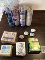 Photo showing all items: four Bath & Body Works fragrance mists, bar soap packs, hair gel in green box, decorative stones with inspirational sayings.