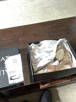 Shoes in original black Naturalizer box with packing paper and size information visible on box label.