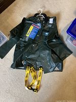 Full view of the Viking Journeyman rain jacket and pants with yellow suspenders, lying flat on carpeted floor with tags visible.