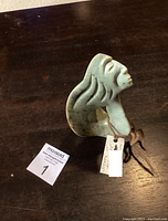 Soap stone sculpture on a wood surface showing front and side views, with a tag labeled 'Seeker of Knowledge'.