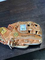 Side view of the tan leather softball glove showing 'Super Deluxe' and 'Pro Sports' stamps, along with the Maxsold auction lot sticker.
