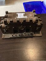 Front view of the dark wooden castle style liquor cabinet with battlement top and metal accents