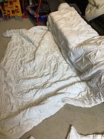 Photo showing the white queen size comforter spread partially on the floor, displaying its tufted floral texture and size.