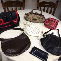 Top view of six women's bags and a black leather wallet displayed on a round table