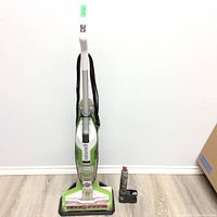 Full front view of the BISSELL CrossWave with attached power cord and the roller brush attachment placed next to the cleaner on the floor.