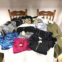 Full lot view of 13 assorted women's clothing items including sweaters, shirts, and dresses arranged on a table.